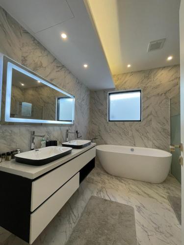 ein Badezimmer mit zwei Waschbecken, einer Badewanne und einem großen Spiegel in der Unterkunft MY HOTEL Al Lathba Pool Villa - Nizwa فيلا اللثبه-نزوى in Nizwa