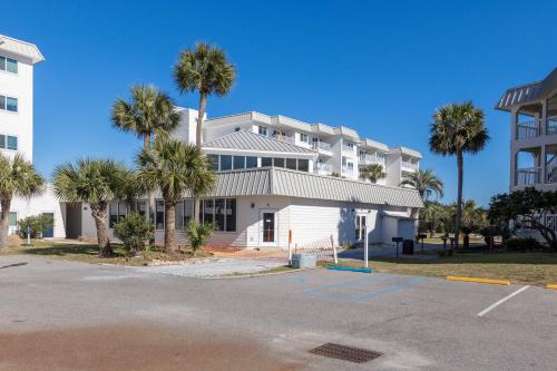 a building with palm trees in front of a parking lot at Plantation 2308 in Gulf Shores