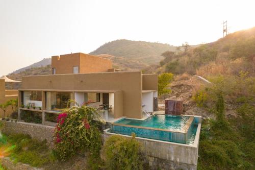 a house with a swimming pool in front of it at StayVista's Sage Scenery - Mountain-View Villa with Infinity Pool & Terrace in Udaipur