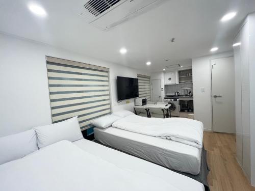 two beds in a white room with a kitchen at 318 Stay in Seoul