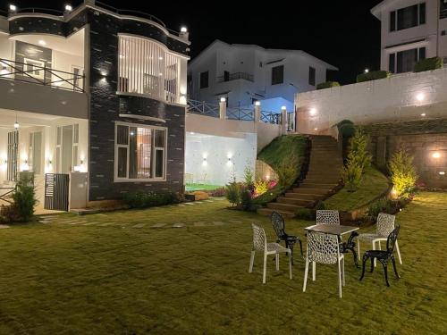 a yard with chairs and a table in front of a house at Orchard Valley View in Ooty