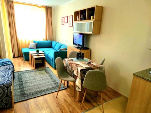 a living room with a blue couch and a table with chairs at Студио D-41 в Апарт-хотел Боровец Гардънс in Borovets