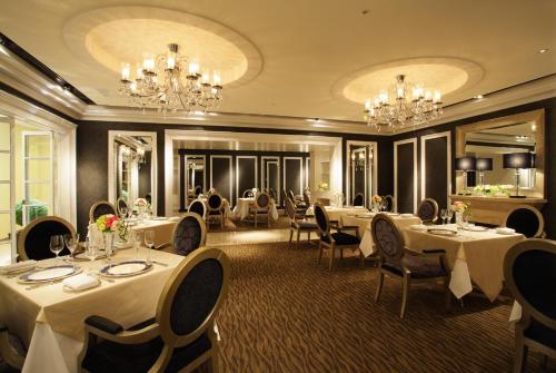 a restaurant with white tables and chairs and chandeliers at Hotel Nikko Osaka in Osaka