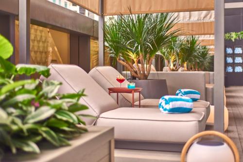 a patio with two white couches and plants at Pullman Singapore Orchard in Singapore
