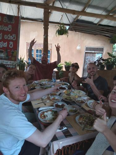 a group of people sitting around a table eating food at Kasun Hotel in Koslanda
