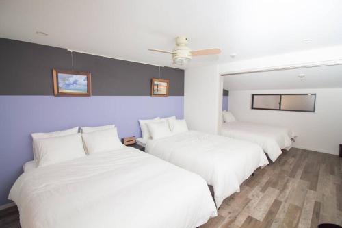 Zimmer mit 3 Betten und weißer Bettwäsche in der Unterkunft D2HOTEL in Osaka