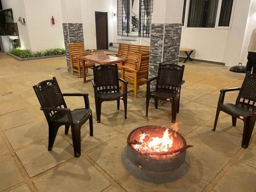 a fire pit in a patio with chairs and a table at Orchard Valley View in Ooty