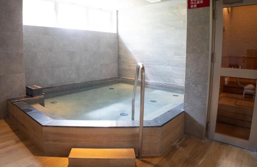 a bath tub with a shower in a bathroom at Hotel Torifito Kashiwanoha in Kashiwa