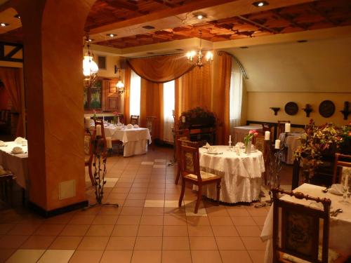 uma sala de jantar com duas mesas com toalhas de mesa brancas em Azymut Hotel & Restaurant em Andrespol