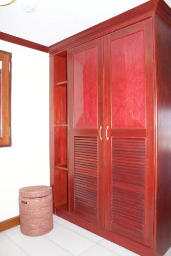 a wooden cabinet with glass doors and a stool at Prince Edouard Apartments & Resort Patong Beach Phuket in Patong Beach