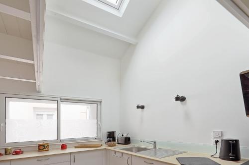 uma cozinha branca com um lavatório e uma janela em La Galerie Pornic - Maison Cedre em Pornic