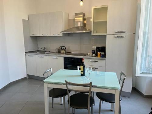 una cocina con mesa y sillas y una botella de vino en Villa Jeanne,appartamento vicino Monaco Vista mare, en Beausoleil