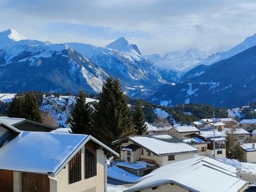 a town with snow covered roofs and mountains at Fleur et Benj in Aussois