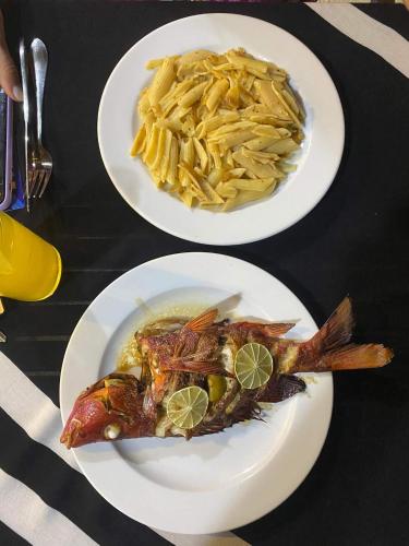 two plates of food with fish and pasta on a table at Rashuthere Maldives in Rasdu