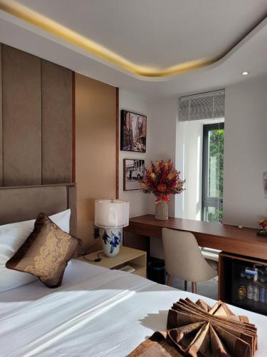 a bedroom with a bed and a desk with a lamp at Ngon Avatar Hotel in Pleiku
