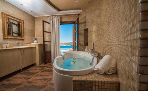 a bathroom with a tub with a view of the ocean at Elounda Maris Villas in Elounda