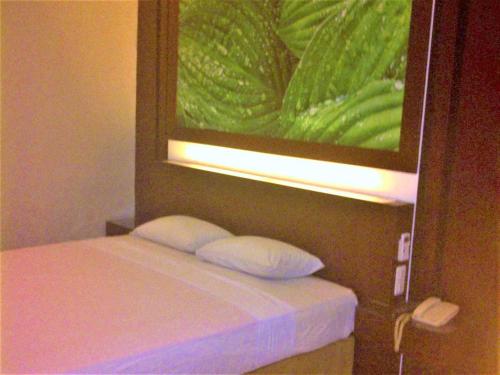 łóżko z dwoma poduszkami siedzącymi pod obrazem w obiekcie Citra Raya Hotel Banjarmasin w mieście Banjarmasin