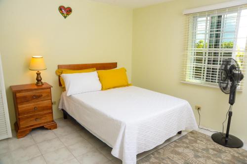 a bedroom with a bed and a fan next to a window at Three Palm Villa in Montego Bay