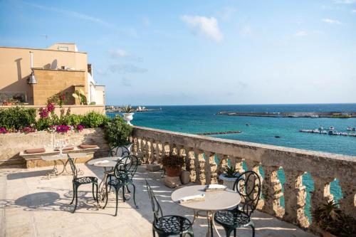 d'une terrasse avec des tables et des chaises donnant sur l'océan. dans l'établissement Palazzo De Mori, à Otrante