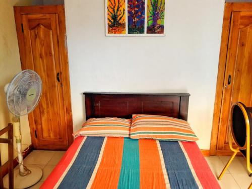 a bed with a colorful striped blanket and a fan at Galkotuwa Estate in Gelioya