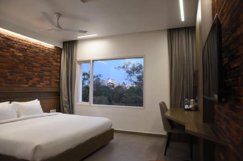a bedroom with a bed and a desk and a window at RATHNA RESIDENCY - Near US CONSULATE in Chennai