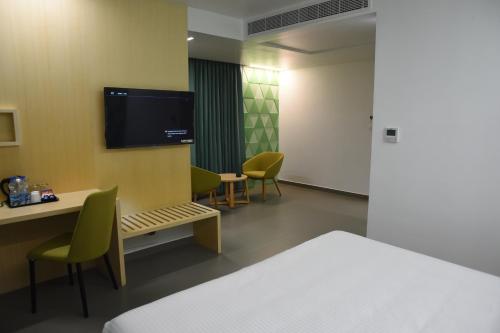 a room with a bed and a tv on a wall at RATHNA RESIDENCY - Near US CONSULATE in Chennai
