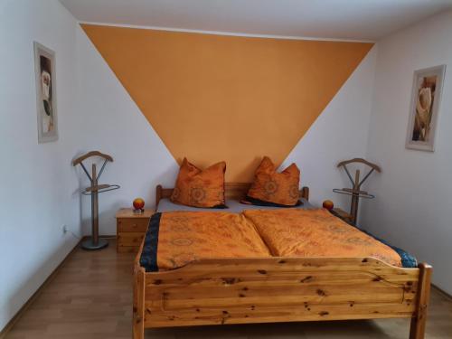 1 dormitorio con cama de madera con sábanas y almohadas de color naranja en Ferienwohnung Eva, en Grebenhain