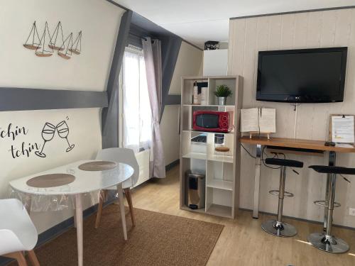 een woonkamer met een tafel en een televisie bij Le cocon sainte Catherine in Honfleur