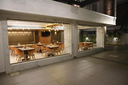 a restaurant with tables and chairs inside of a window at RATHNA RESIDENCY - Near US CONSULATE in Chennai