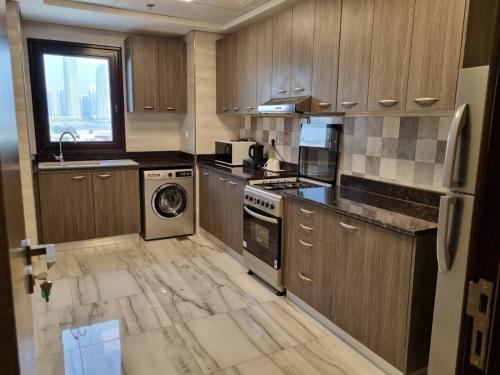 a kitchen with wooden cabinets and a washer and dryer at Grand Stay Holiday Homes Al Jaddaf in Dubai