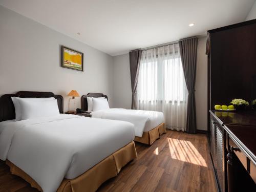 um quarto de hotel com duas camas e uma televisão de ecrã plano em Minasi Premium Hotel em Hanói