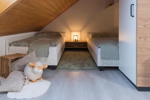 un dormitorio en el ático con 2 camas y un cordero relleno sentado en una alfombra en Hiša Rodica, en Bohinj