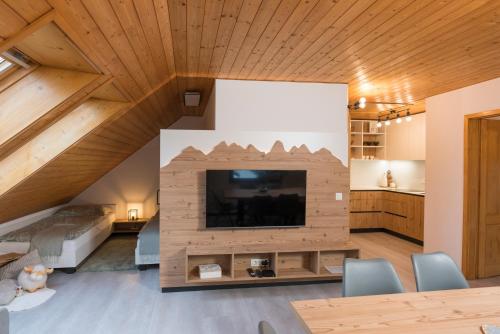 a living room with a large tv in a wooden ceiling at Hiša Rodica in Bohinj