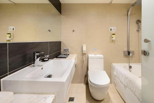 uma casa de banho com um lavatório, um WC e uma banheira em Beacon Hotel em Taichung