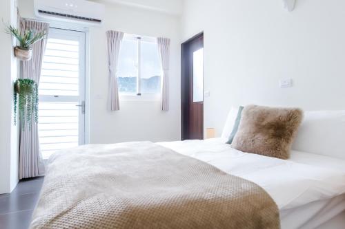 a white bedroom with a large bed with a pillow at Taitung Bear Station Inn in Taitung City