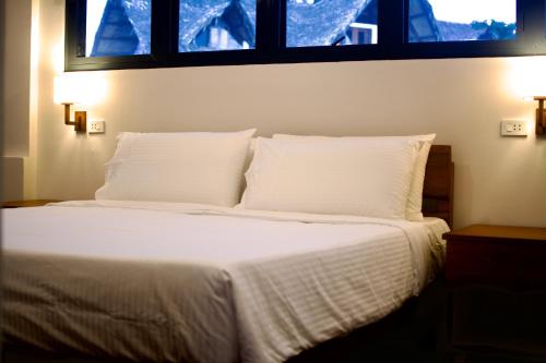 a bedroom with a bed with white sheets and two windows at Private Residences Siargao in General Luna