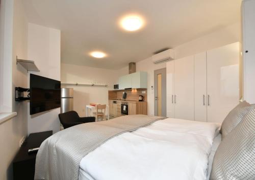 a bedroom with a white bed and a kitchen at EFI Residence Holzova 28 in Brno