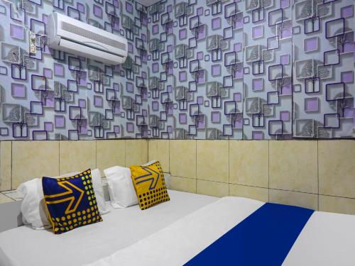 Habitación con cama con almohadas y pared. en SPOT ON 92154 Nusasari Guest House, en Sukabumi