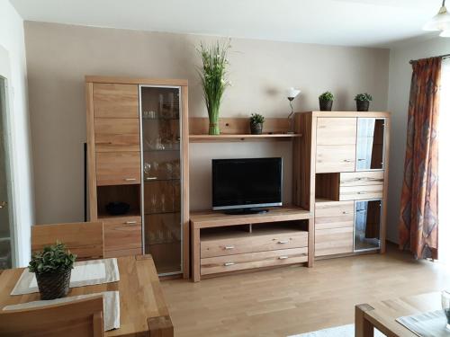 ein Wohnzimmer mit einem TV und einem hölzernen Entertainment-Center in der Unterkunft Appartementhaus Bayern Residenz in Bad Füssing