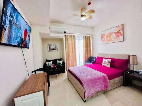 um quarto com uma cama rosa e um sofá em Lengs Place 1 - Studio Unit at Inspiria Condo Beside Abreeza Mall Davao City em Davao