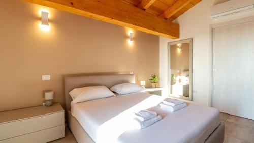 a bedroom with a large white bed and a mirror at Casa Degli Artigiani-Attico con vista in Oristano
