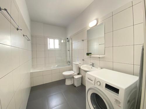 a white bathroom with a washing machine in it at Phaedrus Living Down Town Flat Stephania 302 in Limassol