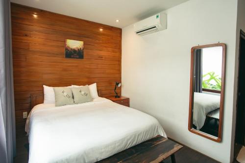 a bedroom with a white bed and a mirror at Kool House in Tuy Hoa