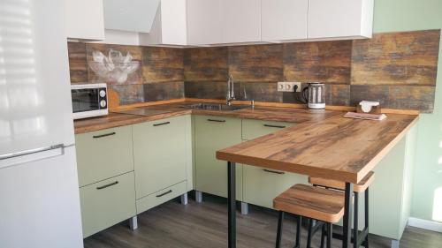 a kitchen with white cabinets and a wooden counter top at Rechnaya in Astana