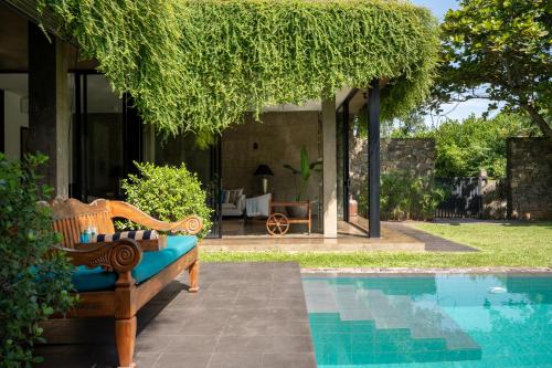 a bench next to a swimming pool next to a house at Tranquil Waters in Negombo
