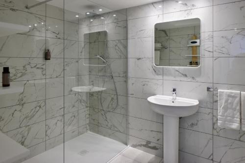 y baño blanco con lavabo y ducha. en Résidence Carlton - Entièrement rénové en Beaulieu-sur-Mer