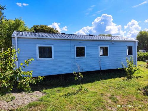 a blue tiny house in a yard at mini-camping 't Bergje in Serooskerke