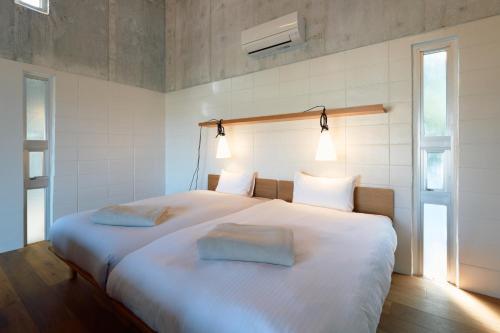 a bedroom with a large white bed with two pillows at オーシャンビューの静かな84平米の空間で暮らすように泊まる宿m yomitan nagahama in Yomitan