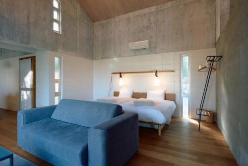 ein Schlafzimmer mit einem Bett und einem blauen Sofa in der Unterkunft オーシャンビュー非日常を味わえる空間プライベートバーベキューm yomitan nagahama in Yomitan