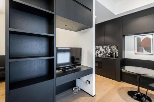 una camera con pareti nere, TV e tavolo di Easylife - Elegante monolocale in Corso Magenta a Milano